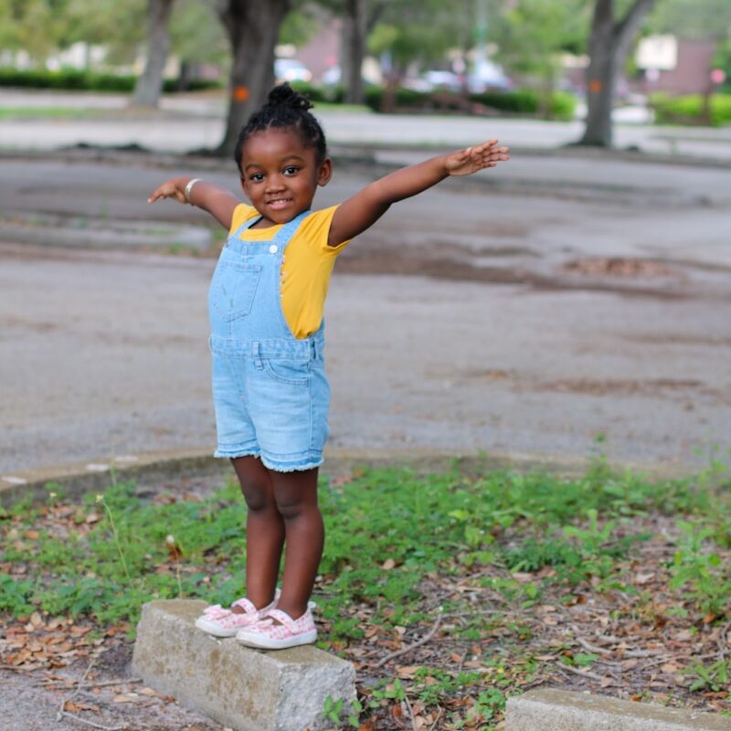 girl in yellow shirt standing on gray concrete blocks during daytime
